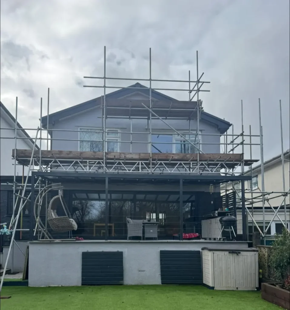 Scaffold with boarded working platform at roof level of a house extension